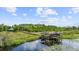 Scenic view of covered dock extending into a serene lake, surrounded by lush wetlands and trees at 13450 E Lake Mary Jane Rd, Orlando, FL 32832