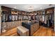 Luxurious walk-in closet with custom shelving, drawers, and central island with seating at 13450 E Lake Mary Jane Rd, Orlando, FL 32832