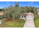 Single-story home with a white garage door and a blue front door, nestled amongst lush green landscaping at 4201 Shadow Wood Dr, Winter Haven, FL 33880