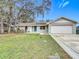 Single story home with a large yard, featuring a white garage and a blue front door at 4201 Shadow Wood Dr, Winter Haven, FL 33880