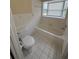 Bright bathroom with a tiled floor and a tub with tile surround under a window at 1024 Driggers Rd, Lakeland, FL 33809