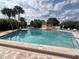 Inviting community pool featuring clear blue water, surrounded by tropical palm trees and lounge chairs at 2055 S Floral Ave # 73, Bartow, FL 33830