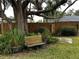 Relaxing backyard oasis with a wooden bench under a large shade tree at 2062 Katie Ct, Winter Haven, FL 33884