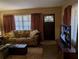 Cozy living room featuring a brown leather sofa, wood floors, and large windows at 217 Bay E St, Davenport, FL 33837