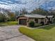 Brick ranch home with a metal roof, two-car garage, and landscaped yard at 3703 White Oak Ct, Lake Wales, FL 33898