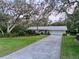 Spacious driveway leading to a charming home with meticulously manicured landscaping and mature trees at 41 Spring Ln, Haines City, FL 33844