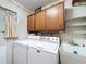 Well-equipped laundry room featuring a washer, dryer, sink, and ample overhead cabinet storage for convenience at 41 Spring Ln, Haines City, FL 33844