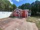 Backyard showcasing a red storage shed with vintage decorations, surrounded by a white fence and paved area at 419 Broward Ter, Winter Haven, FL 33884