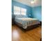 Bright bedroom featuring blue walls, wood floors, and a comfortable bed with floral bedding at 419 Broward Ter, Winter Haven, FL 33884