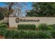 Entrance to Hallamwood community with a large sign surrounded by lush greenery and manicured landscaping at 4523 Hallamview Ln, Lakeland, FL 33813