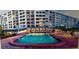Community pool with lounge chairs and umbrellas next to a high rise building with many windows and red brick accents at 700 Mirror Nw Ter # 403, Winter Haven, FL 33881