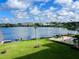 Waterfront view featuring a blue lake, clear sky, lush green lawn, pool, boat docks and landscaped grounds at 700 Mirror Nw Ter # 403, Winter Haven, FL 33881