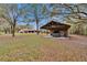 Exterior shot of property featuring an open carport and well-maintained lawn with mature trees at 7929 Chase Rd, Lakeland, FL 33810