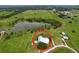 An aerial view of the property and surrounding area featuring a pond, green fields, and other houses at 1040 Timbers Dr, Fort Meade, FL 33841
