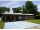 Charming single-story brick home with a well-maintained lawn and mature trees under a sunny blue sky at 112 Bishop St, Auburndale, FL 33823