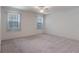 Bedroom featuring plush carpeting, white walls, ceiling fan, and two windows for ample natural light at 1131 Country Oaks Blvd, Lake Wales, FL 33898