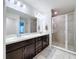 Bathroom featuring a dual sink vanity with dark cabinets and a tiled walk-in shower with glass door at 1205 Third Ct, Eagle Lake, FL 33839