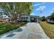 Inviting home exterior featuring a long driveway, covered carport, and mature landscaping at 1575 Longbow Dr, Lakeland, FL 33810