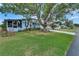 Charming home with a lush lawn, mature tree decorated with birdhouses, and cozy outdoor seating at 1575 Longbow Dr, Lakeland, FL 33810