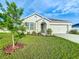 Single-story home with a well-manicured lawn, garden bed, and neutral-colored exterior at 1835 Jackson Oaks Dr, Bartow, FL 33830