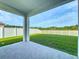 Covered patio overlooks a spacious backyard with lush green grass and a white fence at 1835 Jackson Oaks Dr, Bartow, FL 33830