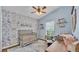Charming Bedroom with beautiful wallpaper, a modern crib, and a ceiling fan for a cozy space at 1850 Saddlewood Pl, Bartow, FL 33830