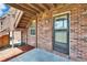 Covered patio with brick walls, concrete floor, and access to a lush backyard through a glass-paned door at 1920 E Edgewood Dr # D7, Lakeland, FL 33803