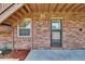 Covered patio with brick walls, concrete floor, and access to a lush backyard through a glass-paned door at 1920 E Edgewood Dr # D7, Lakeland, FL 33803