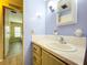 A well-lit bathroom featuring blue walls, wood cabinets and updated fixtures and neutral countertops at 2055 S Floral Ave # 291, Bartow, FL 33830