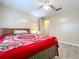 Bedroom features wood-paneled walls, a ceiling fan, and bed with bright red floral patterned blanket at 2055 S Floral Ave # 291, Bartow, FL 33830