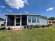 Exterior view of the gray home showcasing the screened-in porch and tidy landscaping at 2055 S Floral Ave # 69, Bartow, FL 33830