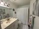 Well-lit bathroom featuring a marble vanity top, white cabinets, and a shower with a white curtain at 294 Winter Ridge Blvd # 294, Winter Haven, FL 33881