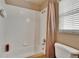 Bright bathroom with a bathtub featuring white tile, a shower head, and a beige shower curtain at 3154 Prairie Dunes W Cir, Lakeland, FL 33810