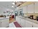 Bright kitchen featuring white cabinetry, a double sink, and views to the living room at 3154 Prairie Dunes W Cir, Lakeland, FL 33810