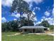 Charming single-story home with a covered porch, set amidst mature trees and blue skies at 4140 Old Dixie Hwy, Auburndale, FL 33823