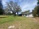 Quaint single-story home with white stucco siding, dark shutters, and a spacious yard with mature trees at 4151 Boggy Creek Rd, Kissimmee, FL 34744