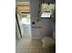 Compact bathroom with toilet, grab bar, and window featuring floral curtains; view extends to pool area at 4805 Oak Acres Dr, Lake Wales, FL 33898