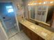 Bathroom features a granite countertop, wooden cabinets and framed mirror with decorative backsplash and tiled floors at 4805 Oak Acres Dr, Lake Wales, FL 33898