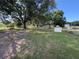 Grassy backyard with mature trees, storage buildings, and chain link fence at 5138 Rock Dove Trl, Lakeland, FL 33810