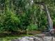 Lush backyard featuring a fire pit, seating area, and a tranquil water feature surrounded by greenery at 5427 Orange Valley Dr, Lakeland, FL 33813