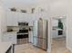 Well-lit kitchen boasting stainless steel appliances, white cabinetry, and a view leading to a laundry room at 5427 Orange Valley Dr, Lakeland, FL 33813
