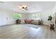 Bright living room featuring hardwood floors, ceiling fan, and large windows overlooking lush greenery at 603 Solana St, Lakeland, FL 33813