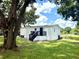 Home exterior in backyard with mature trees, green grass and black deck with stairs at 6611 Glen Meadow Loop, Lakeland, FL 33810
