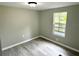 Bedroom featuring laminate flooring, gray walls, and a window overlooking the front yard at 6611 Glen Meadow Loop, Lakeland, FL 33810