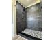 Modern shower with gray tile surround and mosaic tile flooring at 7005 Dove Meadow Trl, Lakeland, FL 33810
