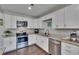 Kitchen featuring stainless steel appliances, white cabinets, granite countertops, and wood-look floors at 733 S Clayton Ave, Lakeland, FL 33801