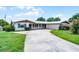 Inviting single-story home with a long driveway leading to an attached garage at 900 Howard Nw Ter, Winter Haven, FL 33881