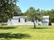 Well-maintained white house with a green lawn, offering a peaceful and inviting curb appeal at 9625 Moore Rd, Lakeland, FL 33809
