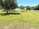 Lush green yard with mature trees, and a white house on a sunny day at 9625 Moore Rd, Lakeland, FL 33809