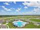 Aerial view showcasing community pool and surrounding neighborhood under a beautiful blue sky with puffy clouds at 3528 Dahlia Dr, Haines City, FL 33844